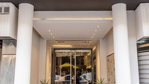 A hotel entrance with a glass door, potted plants, and a tiled floor. - Hotel M (Mendoza)