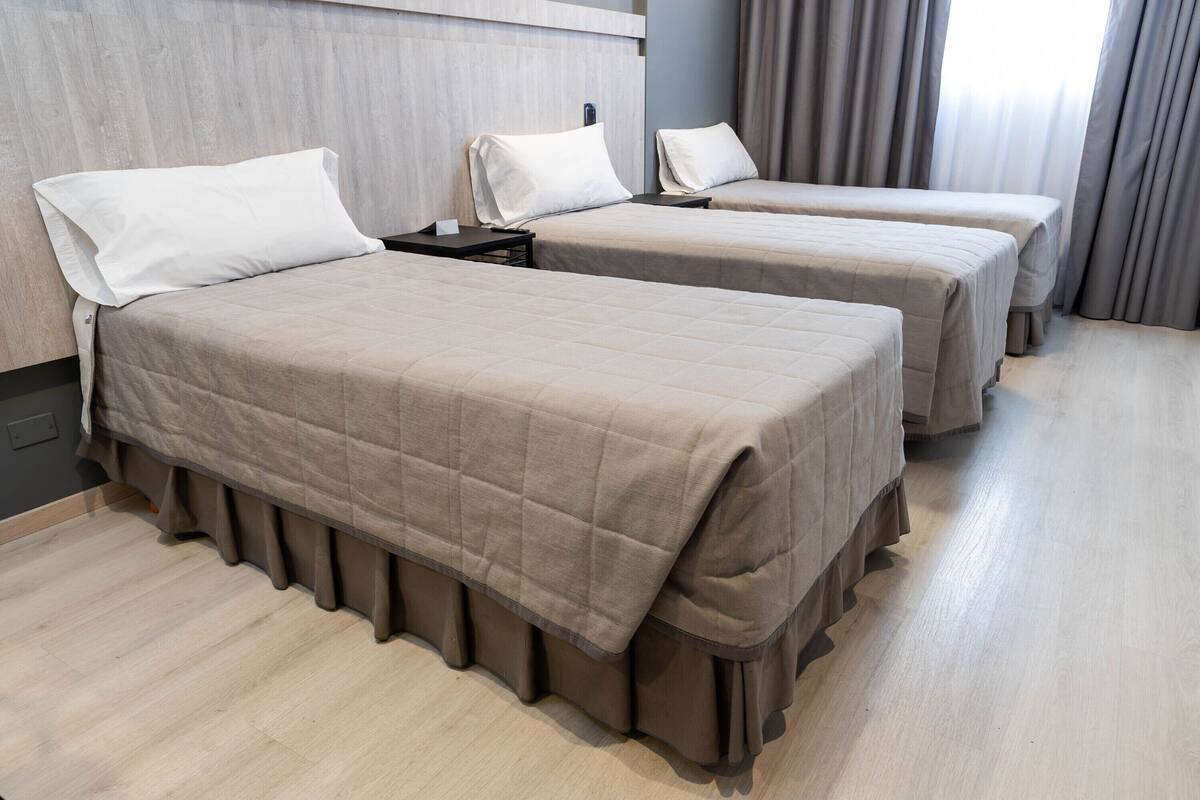 A hotel room with two beds, a nightstand, and a wooden headboard.