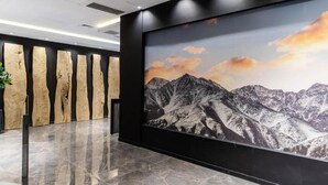 A lobby with a large mountain landscape mural, wooden wall panels, and a marble floor. - Hotel M (Mendoza)
