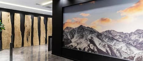 A lobby with a large mountain landscape mural, wooden wall panels, and a marble floor.