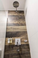 Un baño moderno con diseño de pared de madera, un cabezal de ducha y un inodoro.