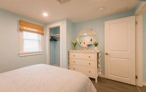 A bedroom with a bed, a dresser, a mirror, a door, and a closet. - Oceanfront Escape—Cape Cod Bay & Sandbars (East Sandwich)