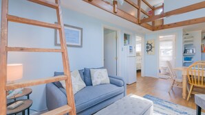 Un salon chaleureux avec un canapé bleu, une échelle en bois et un certificat encadré accroché au mur.