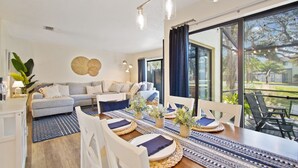 Uma sala de estar moderna com área de jantar, janelas amplas e vista para o exterior.