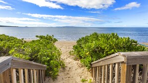 A wooden pathway leading to a beach with lush greenery on either side. - Sugar Beach beauty, Your 2bd Oceanfront Escape (Kihei)
