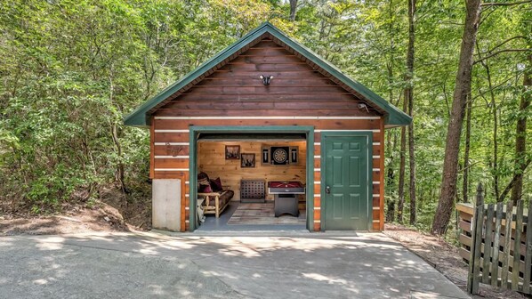 A wooden cabin with a green door, a fireplace, and a dartboard.
