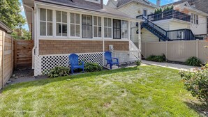 A two-story house with a covered patio, a wooden fence, and a small garden area. - Oak Park, IL, entire house, short walk to train. (Oak Park)