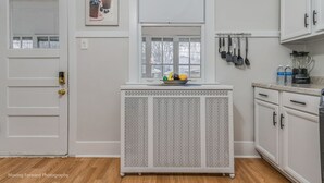 A kitchen with white cabinetry, a fruit bowl on a console table, and a window with a view of houses. - Oak Park, IL, entire house, short walk to train. (Oak Park)