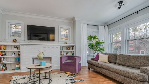 A living room with a fireplace, bookshelves, a television, a purple chair, a brown sofa, and a large window. - Oak Park, IL, entire house, short walk to train. (Oak Park)