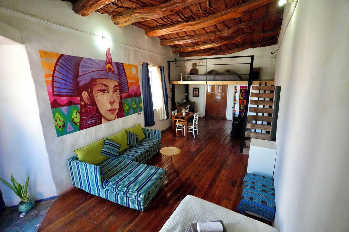 A cozy living area with a striped sofa, a small round table, and a colorful mural on the wall.