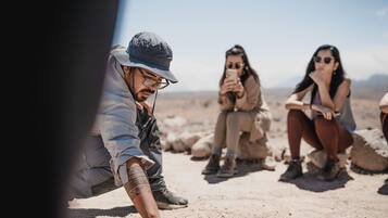 A group of people sitting on a rocky surface outdoors.