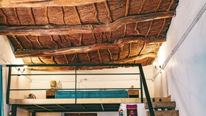 A rustic room with a wooden ceiling, a bunk bed, a wooden staircase, and a dining area with a table and chairs. - Vientos - La Yareta (San Pedro de Atacama)