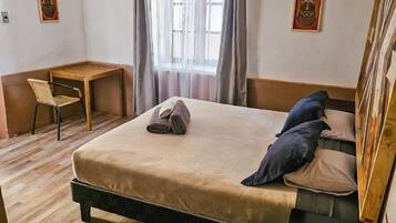 Un dormitorio con cama, escritorio, silla y ventana con cortinas.