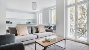 A modern living room with a grey sofa, a coffee table, and a view of the outdoors through large windows. - Sleek Vorstädte 3.5 Room w/ W/D & Storage, 2 min to Market, by Blueground (Basel)
