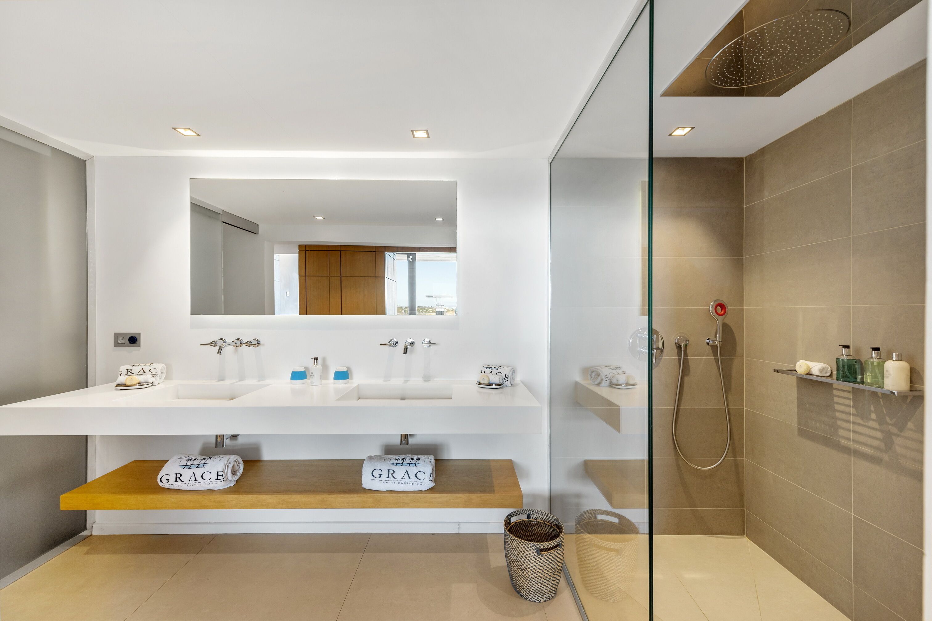 Une salle de bain moderne avec deux lavabos, un grand miroir et un espace douche.