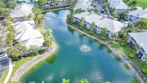 Un barrio residencial con una fuente central rodeada de casas con techos inclinados y palmeras.