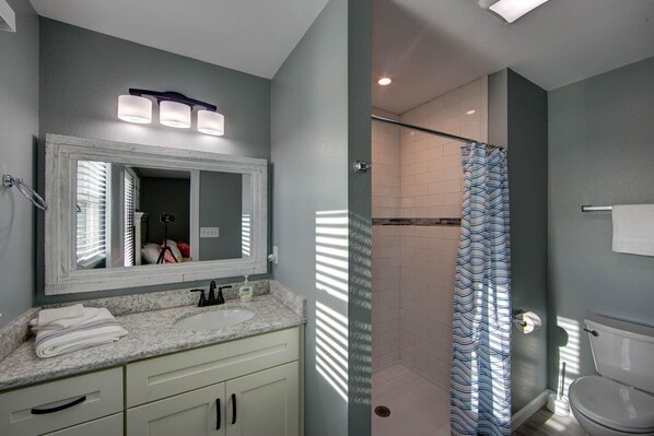 A bathroom with a sink, mirror, and shower.
