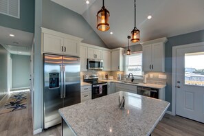 A modern kitchen with white cabinets, stainless steel appliances, and a granite island.