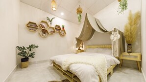 A modern bedroom with a wooden bed, white bedding, hexagonal shelves, hanging plants, and a bedside lamp. - Chivo House - The House Of Peace (Thành phố Đà Lạt)