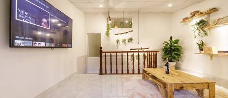 A modern room with a wooden table, a TV mounted on the wall, and a staircase with a railing.