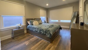 A bedroom with a bed, nightstands, a dresser, and large windows with blinds. - 1.3 miles from Disneyland (Anaheim)