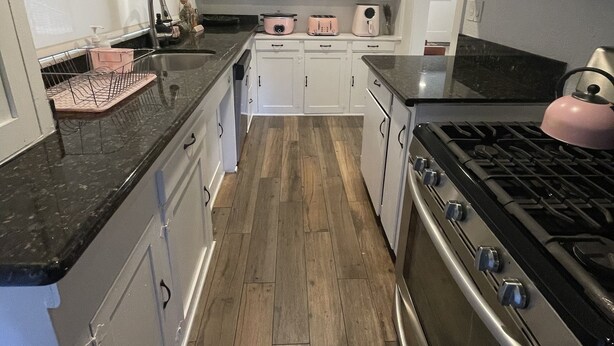 A modern kitchen with white cabinets, a stainless steel stove, and a wooden floor. - 1.3 miles from Disneyland (Anaheim)