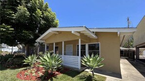 A single-story house with a covered porch, surrounded by a well-maintained lawn and a few small trees. - 1.3 miles from Disneyland (Anaheim)