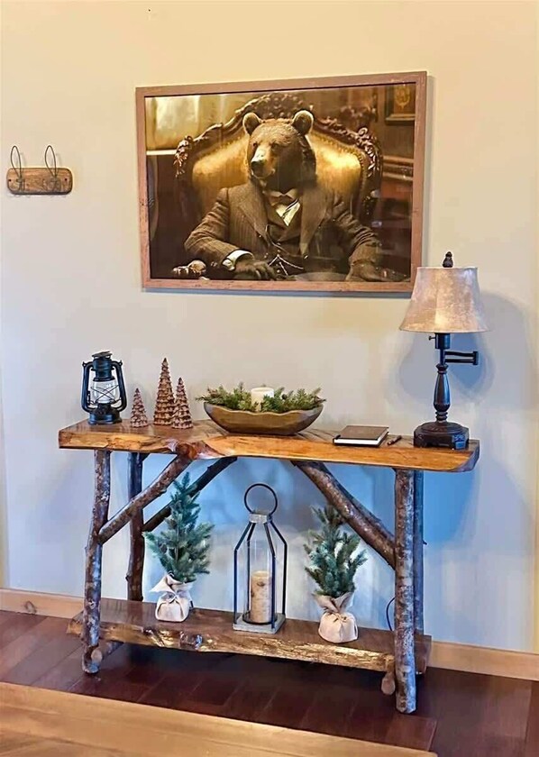 A rustic console table with a bear statue, a lantern, pine cones, and a lamp. - The Debonair Bear (Blue Ridge)