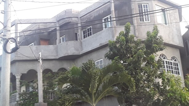 Un immeuble à plusieurs étages doté de balcons, d’une façade en béton et d’une entrée fermée par un portail.