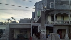 Un bâtiment à deux étages doté d’un balcon, d’une entrée fermée par un portail et d’un escalier menant à l’étage supérieur.