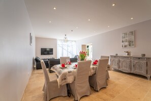 A dining area with a table set for four, a sofa, a TV, and a cabinet.