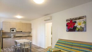 A compact living space with a kitchenette, a dining area, and a sofa. - Lovely apartment for 5 people with WIFI, A/C, pool, TV and terrace (Jesolo)