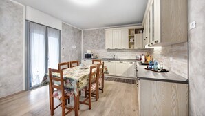 A modern kitchen with wooden cabinets, a dining table with chairs, and a microwave. - Holiday Apartment "Casa Tovini" with Mountain View, Terrace & Wi-Fi (pisogne)