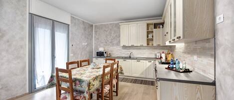 Una cocina moderna con armarios de madera, una mesa de comedor con sillas y un microondas.