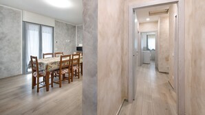 A spacious room with a dining table, chairs, and a kitchen area visible through an open door. - Holiday Apartment "Casa Tovini" with Mountain View, Terrace & Wi-Fi (pisogne)