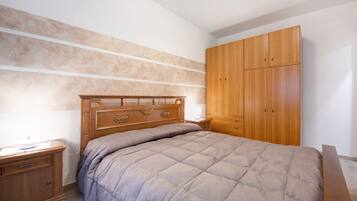 Un dormitorio con cama, armario de madera, mesita de noche y cómoda.