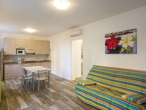 A compact living space with a kitchenette, a dining area, and a sofa.