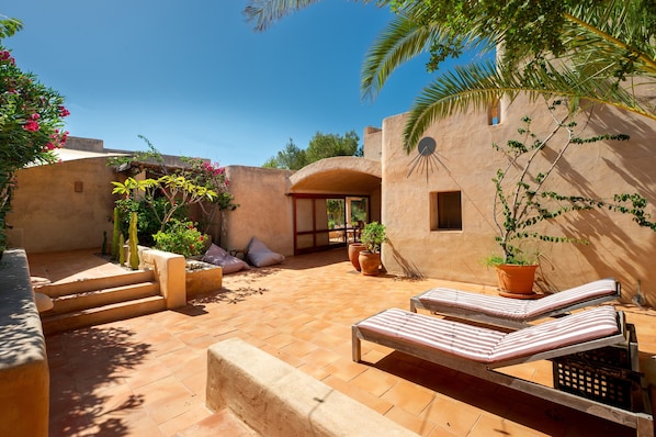 A courtyard with lounge chairs, potted plants, and a staircase.
