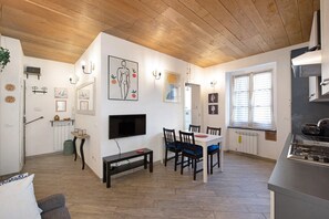 A modern kitchen with a built-in stove, a dining area with a table and chairs, and a television mounted on the wall.