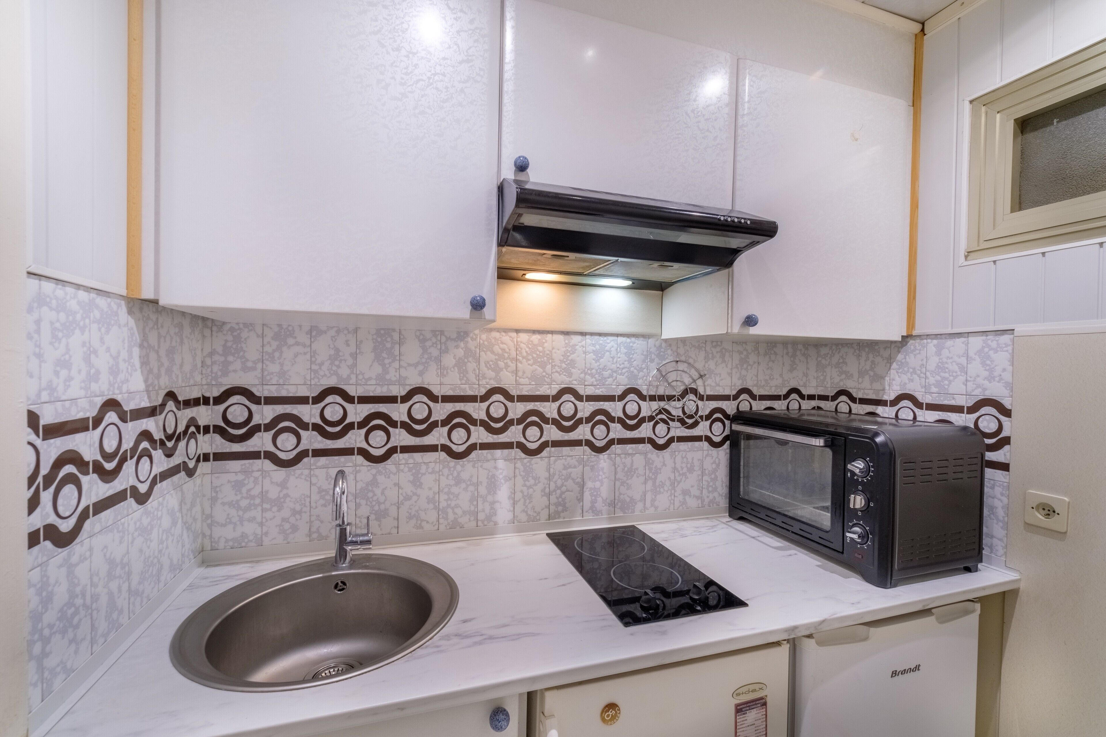 A compact kitchenette with a sink, a stovetop, a microwave, and a built-in oven.