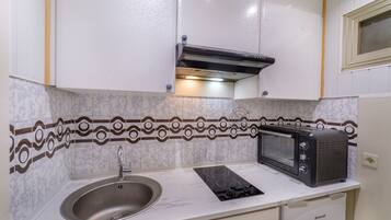 A compact kitchenette with a sink, a stovetop, a microwave, and a built-in oven.