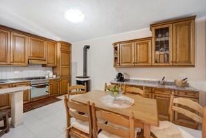 A kitchen with wooden cabinets, a dining table with chairs, a stove, and a range hood.