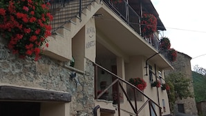 A building with a stone facade, a balcony with red flowers, and a sign reading 'NONNA ANNETTA.'