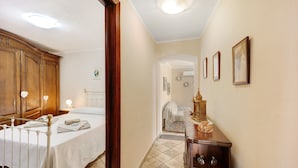 A bedroom with a bed, wooden wardrobe, and a small bedside table with a lamp.