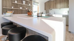 Une cuisine moderne dotée d’un grand îlot central, de meubles en bois et d’une hotte aspirante intégrée.