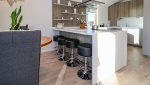Une cuisine moderne dotée d’un îlot central, de tabourets de bar et d’un luminaire suspendu.