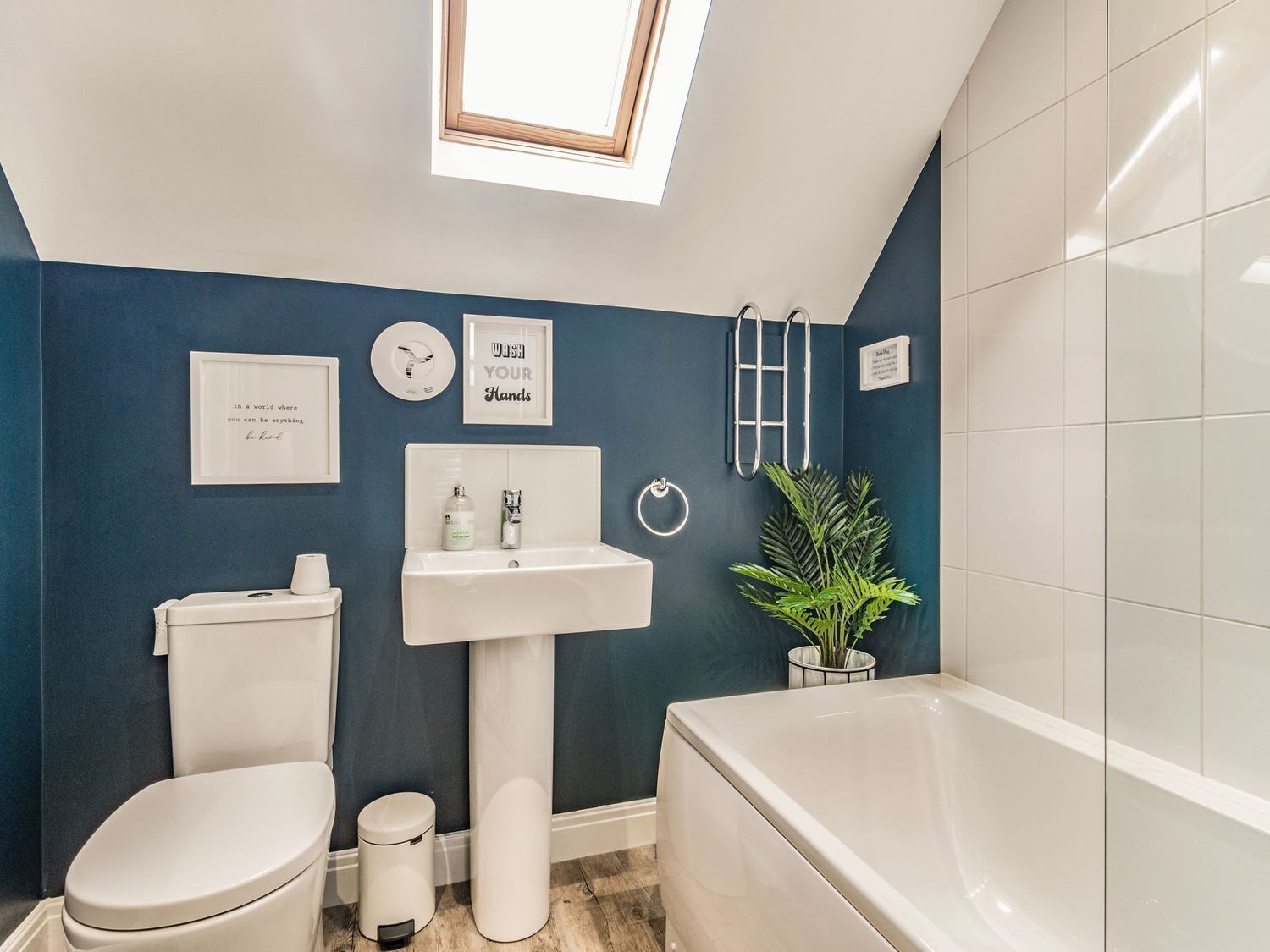 A modern bathroom with a skylight, a toilet, a sink, and a bathtub.