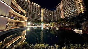 A modern hotel complex with multiple high-rise buildings, a central reflecting pool, and well-lit outdoor areas. - Cozy 1BR cityview with Balcony and near Airport (Paranquae)