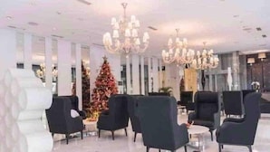 A modern lobby with black armchairs, a Christmas tree, and chandeliers. - Cozy 1BR cityview with Balcony and near Airport (Paranquae)