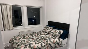 A bedroom with a bed, a window, and a radiator.